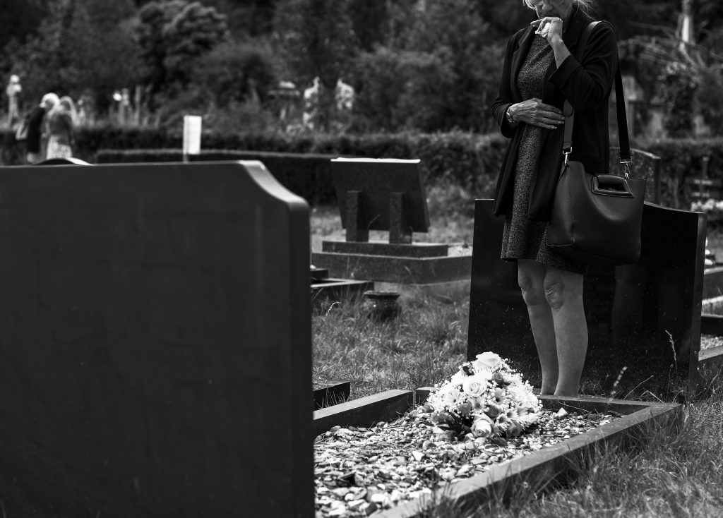 woman in black standing at graveside.