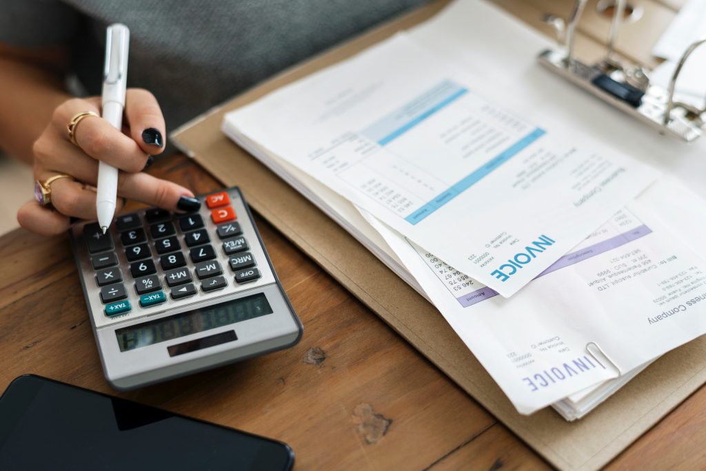 Woman holding a pen near a calculator.