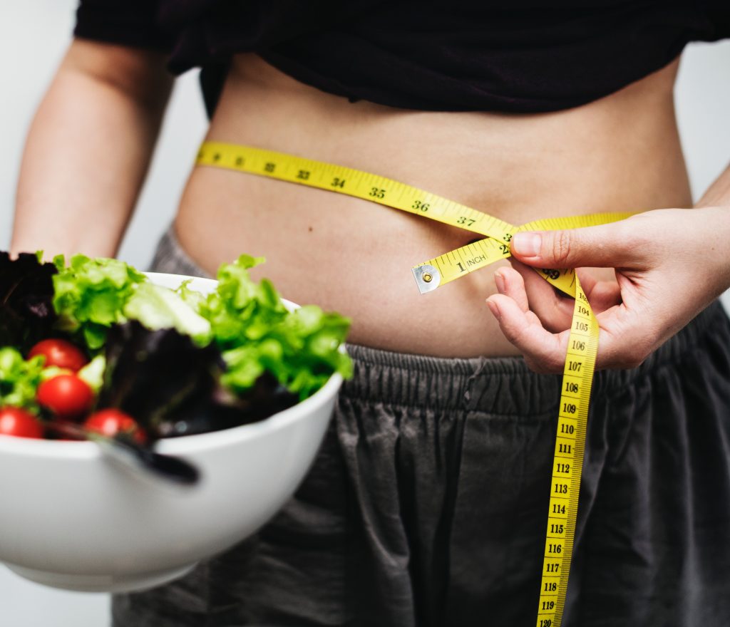 person with tape measure round their stomach